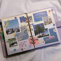 an open planner book with pictures and photos on the pages, sitting on top of a bed