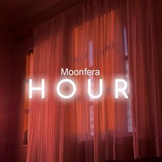 the words moontera hour are lit up in front of an open window with red curtains