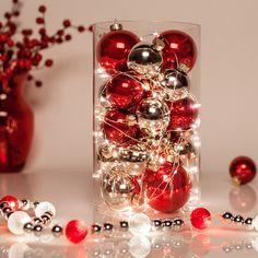 a vase filled with red and white ornaments on top of a table next to christmas lights