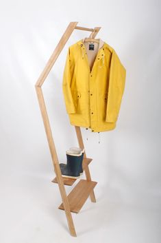 a yellow jacket is hanging on a clothes rack with a hat and boots in it