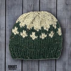 a green and white knitted hat sitting on top of a wooden floor