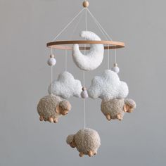 three white sheep hanging from a wooden frame