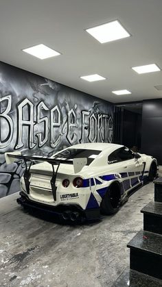 a white sports car parked in front of a graffiti covered wall with stairs leading up to it