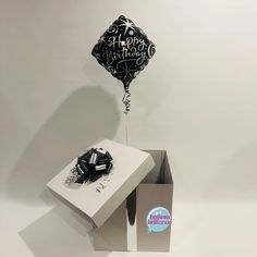 a black and white happy birthday balloon in a box next to a card with the words happy birthday on it