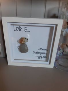 there is a framed picture with a rock in the middle and writing on it that says love is