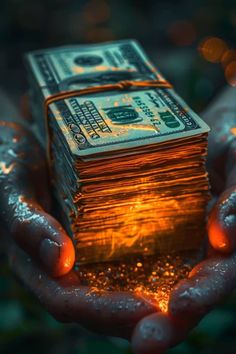 a person's hands holding stacks of money in front of the camera with water droplets on them