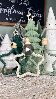 small knitted christmas trees in front of a chalkboard sign that says christmas trees