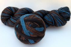 two skeins of blue and brown yarn sitting on top of each other in front of a white background