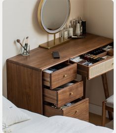 a wooden desk with drawers and a mirror on it's wall next to a bed