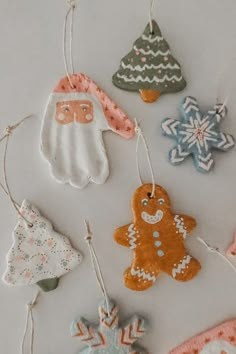 christmas ornaments are hanging from strings on a white tablecloth with snowflakes and other decorations