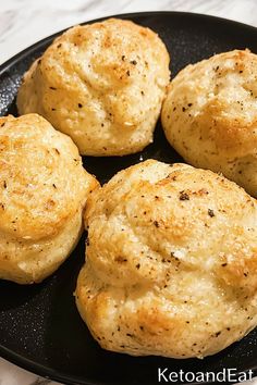 four biscuits in a black pan on a marble counter top with the words keto and eat written above them