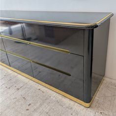 a black and gold dresser sitting on top of a hard wood floor next to a wall