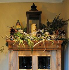 an old cabinet is decorated with pine cones and greenery