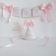 a pink and white two year birthday banner with a party hat on the bottom, tied to it's sides