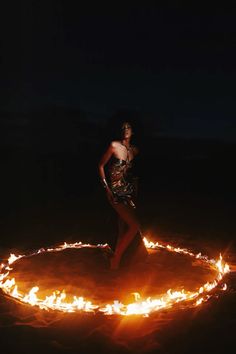 a woman standing in the middle of a circle of fire