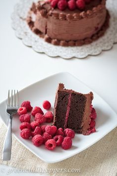 a piece of chocolate cake with raspberries on the side and a fork next to it