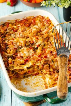 a casserole dish with meat, cheese and vegetables in it next to a spatula