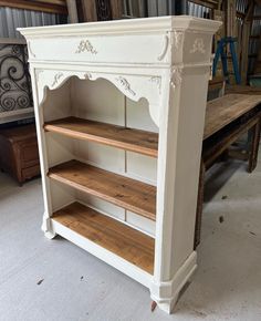 an antique white bookcase with wooden shelves