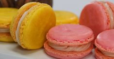 some pink and yellow macaroons are on a white plate