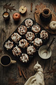 cinnamon rolls with icing on a tray next to an apple and cup of coffee