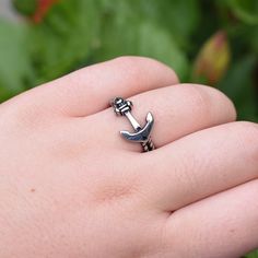 a person's hand holding a ring with an anchor on it