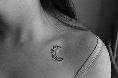 a woman with a tattoo on her shoulder that has the moon and flowers in it