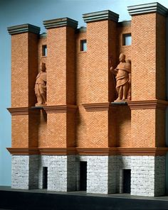 three statues on the side of a brick building