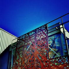 an artistic metal screen on the side of a building with blue skies in the background