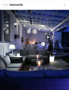 an outdoor living area with couches and lights on the ceiling is lit up at night