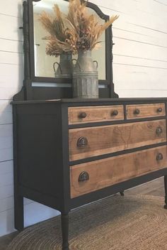 an old dresser with a mirror and vase on top