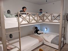 two children sitting on bunk beds in a room with white walls and wood flooring