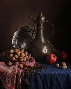 a still life with nuts in a bowl and a pitcher on a table cloth next to an apple