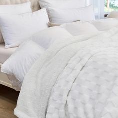 a bed with white comforters and pillows on it