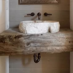 a bathroom sink made out of driftwood in front of a painting on the wall