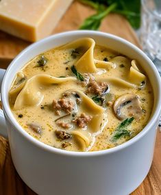 a white bowl filled with soup on top of a wooden table next to a slice of cheese