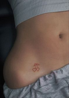 a woman's stomach with an orange heart tattoo on her left side ribcage