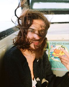 a woman with her hair blowing in the wind while sitting on top of a bus