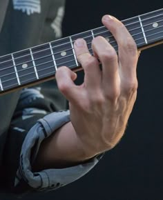 a close up of a person playing an electric guitar with their hands on the strings