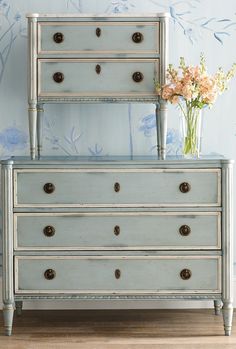 an old dresser with flowers in vases on top