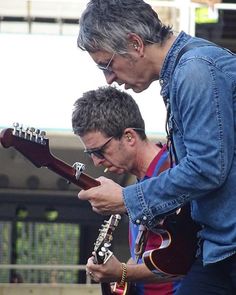 two men are playing guitars on the street