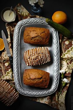 three muffins on a metal tray next to oranges