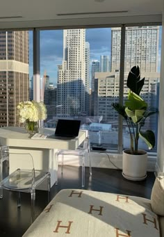 a living room filled with furniture and a large window overlooking a cityscape in the distance