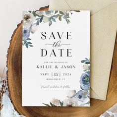 an elegant floral save the date card on top of a wooden slice with lace and flowers