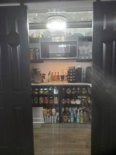 an open door leading into a kitchen with lots of food on the counter and cupboards