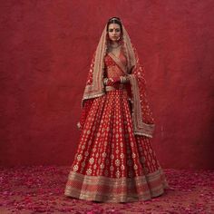 a woman in a red and gold bridal gown standing next to a red wall