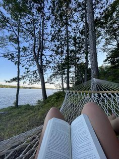 a person reading a book in a hammock by the water with trees on both sides