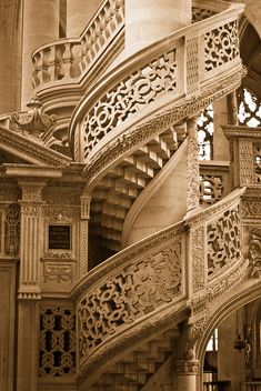 an old photo of a spiral staircase in a building with intricate carvings on the railings