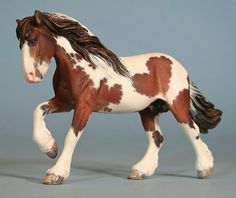 a brown and white toy horse with black spots on it's head, standing in front of a blue background