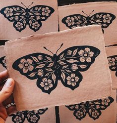 a person holding up some paper with black and white butterflies on it