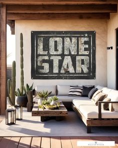 an outdoor living area with couches, tables and cacti in front of a lone star sign